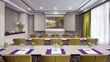 A conference room with a long table, yellow chairs, and a projector screen displaying a scenic image.