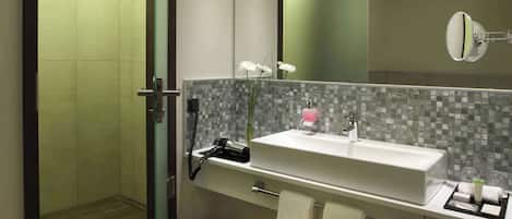 A modern bathroom with a glass shower door, a large mirror, and a vanity with a sink and towel rack.