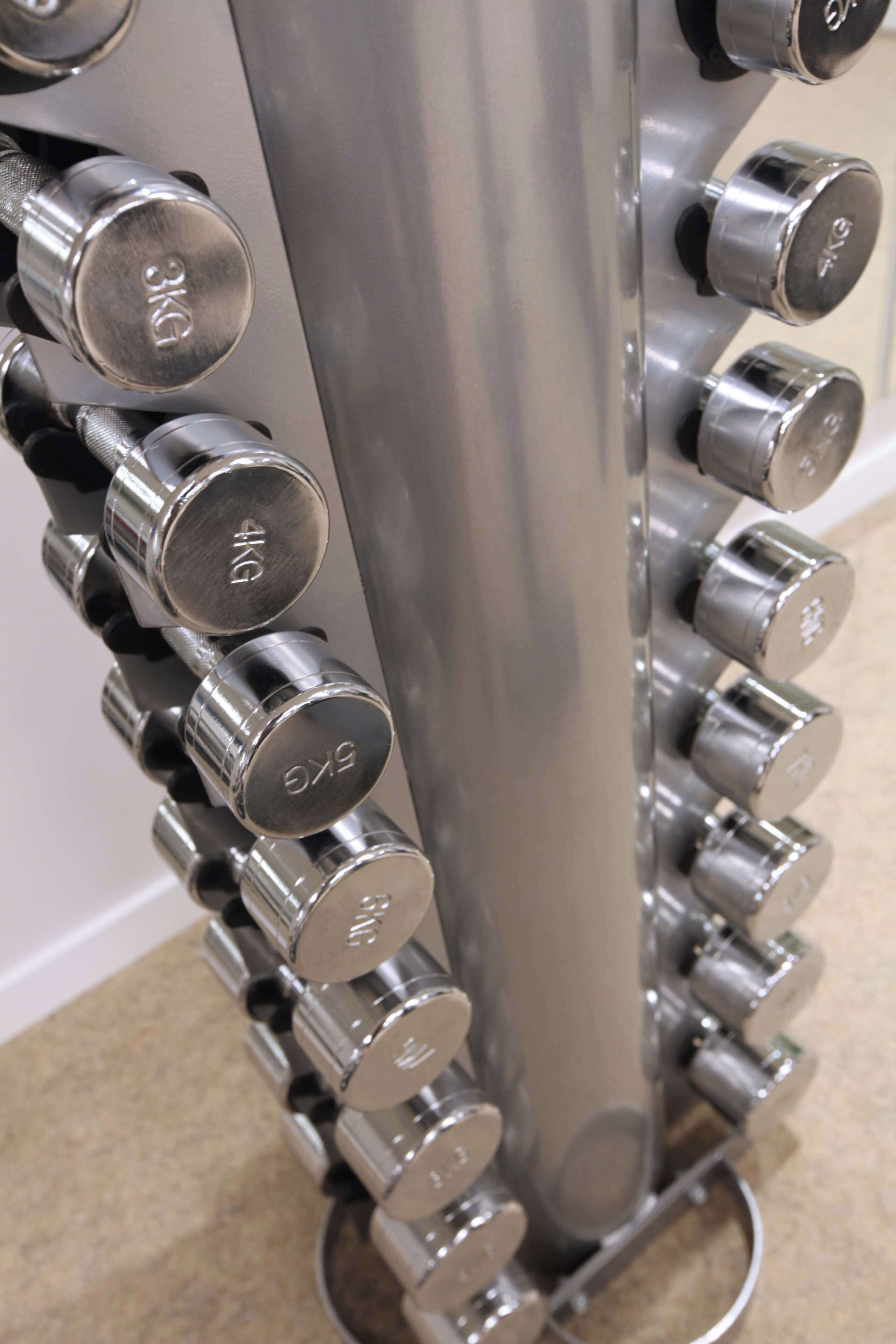 A close-up of a metallic dumbbell rack with weight markers.