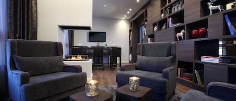 Ein modernes Wohnzimmer mit zwei grauen Sesseln, einem Couchtisch und einem Bücherregal mit Dekoration.