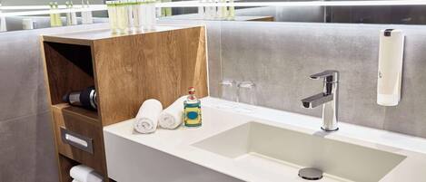 Un baño moderno con un lavamanos grande, un estante de madera con toallas y un espejo sobre el lavamanos.