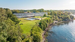 A large hotel with a swimming pool and a view of a river.