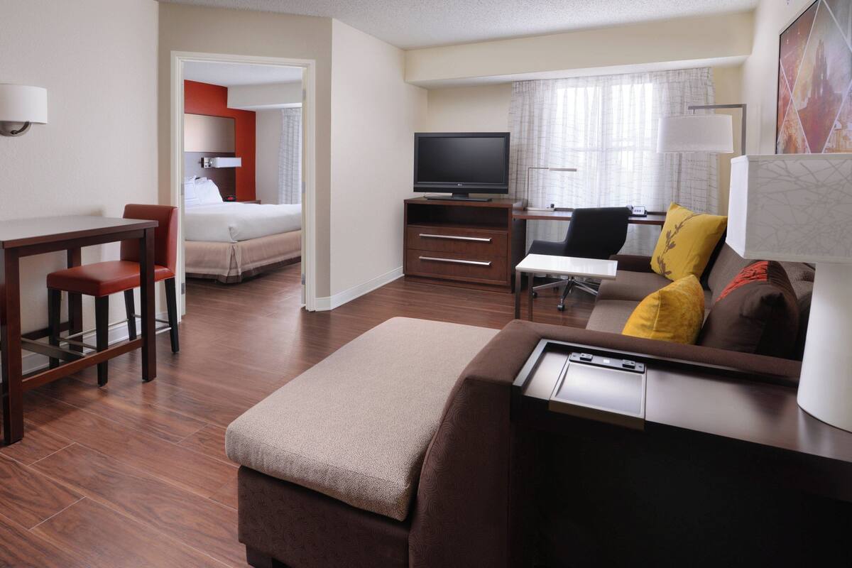 Ein Hotelzimmer mit einem Bett, einem Fernseher, einem Schreibtisch, einem Sessel und einem Schlafsofa.