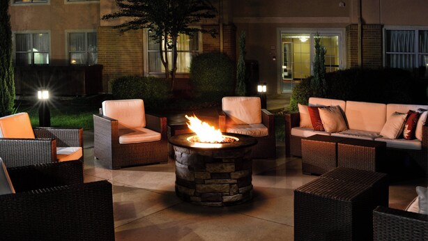 An outdoor seating area with wicker furniture and a stone fire pit. - Residence Inn By Marriott San Antonio Airport/Alamo Heights (San Antonio)