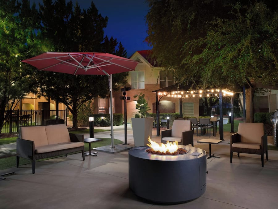 An outdoor patio area with a fire pit, seating, and string lights.