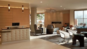 A modern lobby with a reception desk, seating area, and a large window. - DoubleTree Suites by Hilton Hotel Boston - Cambridge (Boston)