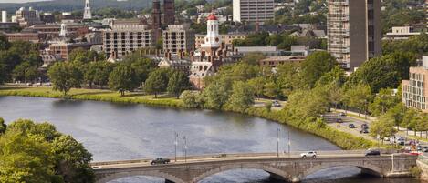 A river with a stone bridge, a boat, and buildings in the background.
