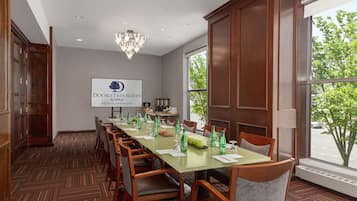 A conference room with a long table, chairs, a chandelier, and a sign for DoubleTree Suites by Hilton in Boston-Cambridge.