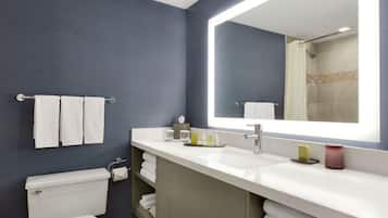Un baño moderno con un espejo grande, lavamanos blanco y un inodoro.