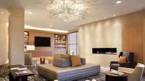 A modern hotel room with a large bed, a fireplace, a TV, and a seating area with a coffee table. - DoubleTree Suites by Hilton Hotel Boston - Cambridge (Boston)