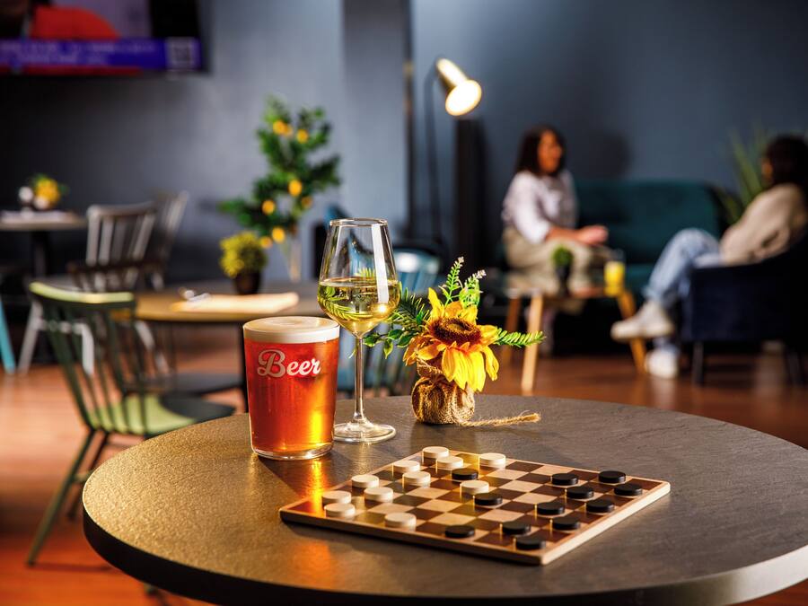 Una mesa redonda con una jarra de cerveza, una copa de vino y un tablero de ajedrez.