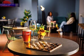 Ein runder Tisch mit einem Bierkrug, einem Weinglas und einem Schachbrett.