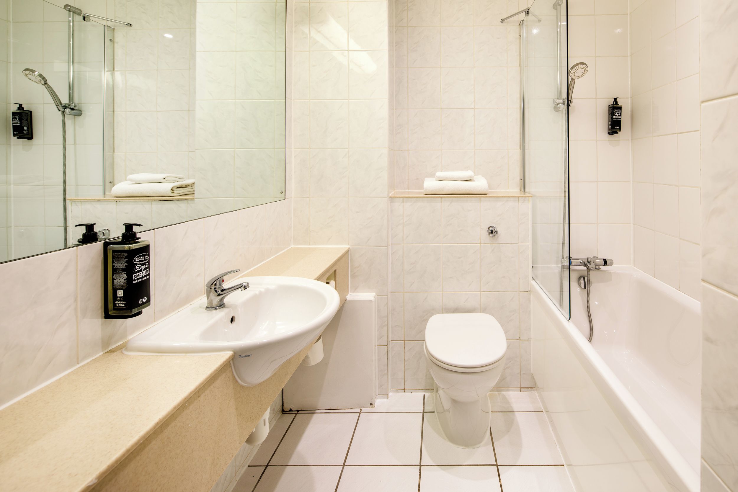 Un baño moderno con lavamanos, inodoro y zona de ducha.