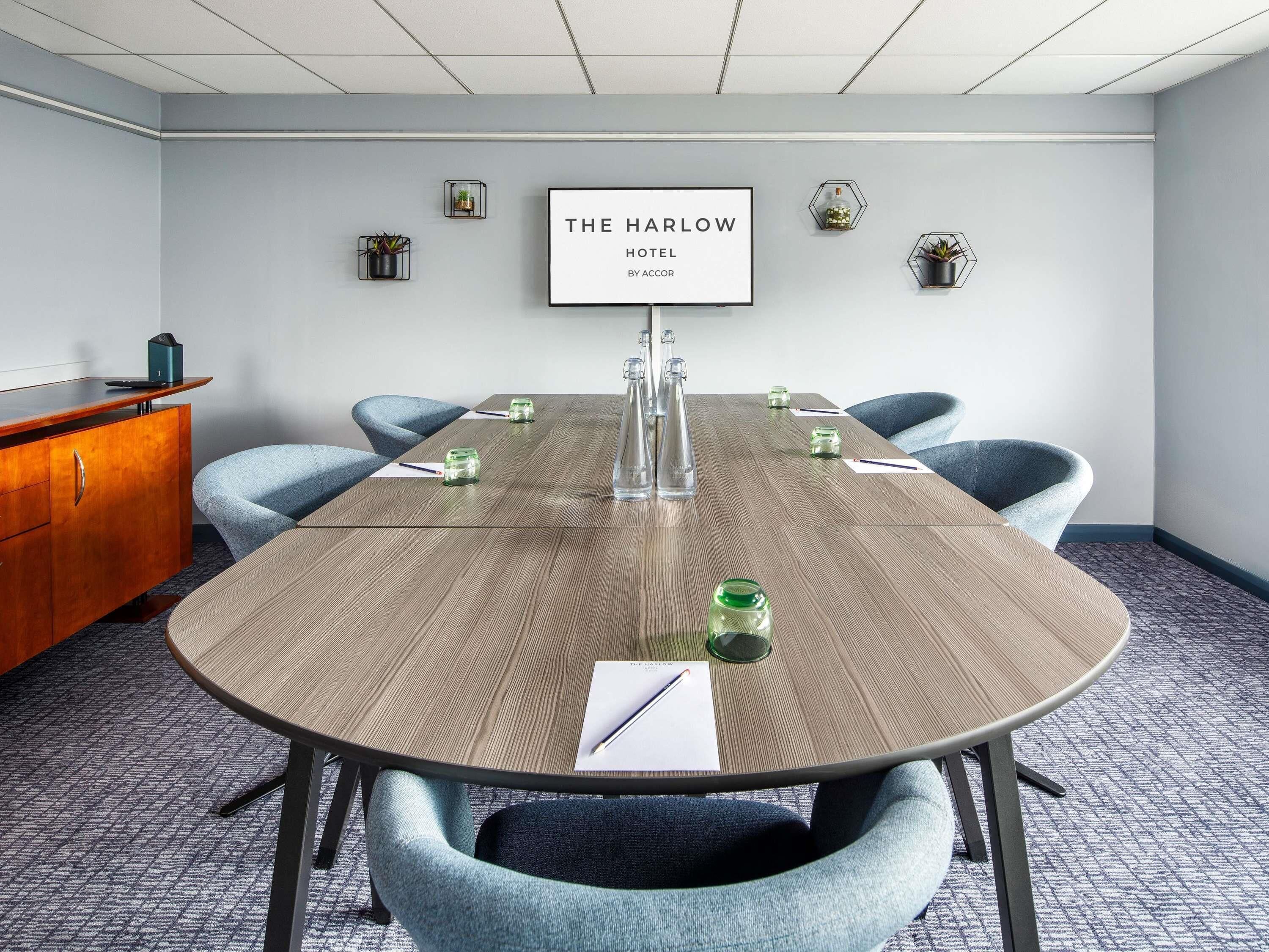 A conference room with a wooden table, six chairs, a framed sign on the wall, and a wooden cabinet.