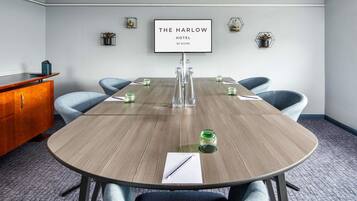 A conference room with a wooden table, six chairs, a framed sign on the wall, and a wooden cabinet.