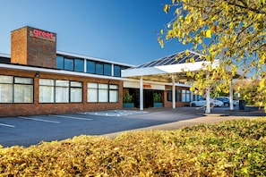 A building with a 'Great' sign, a parking lot, and a covered entrance area. - greet London Harlow (Harlow)