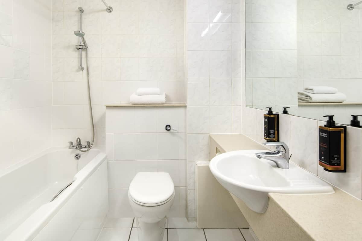 Een moderne badkamer met een bad, toilet en wastafel.