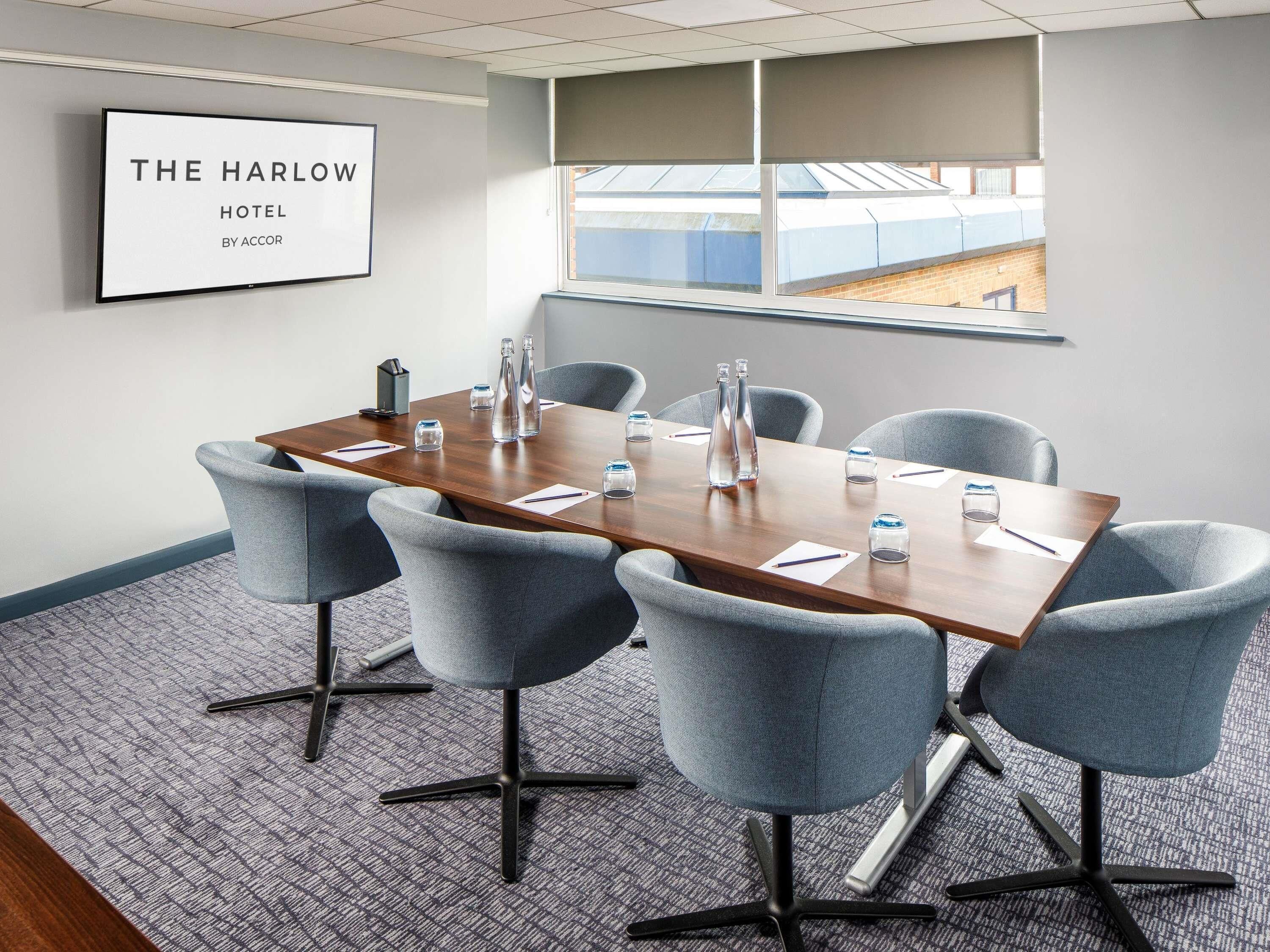 A conference room with a wooden table, grey chairs, and a framed sign on the wall.
