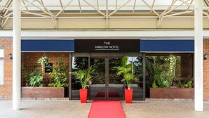 A hotel entrance with a red carpet, brick facade, and a sign reading 'The Harlow Hotel.' - The Harlow Hotel By AccorHotels (Harlow)