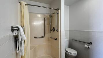 A bathroom with a walk-in shower, grab bars, a toilet, and a towel rack.