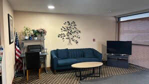 Ein Wohnzimmer mit blauem Sofa, einem kleinen Tisch, einem Fernseher und einer Wanddekoration.