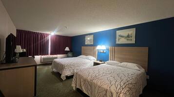 A hotel room with two beds, a desk, a chair, a lamp, and a picture on the wall.