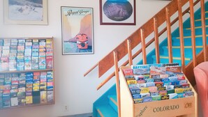 A travel agency office with a wooden staircase, a wall display of travel brochures, and framed pictures of Colorado attractions. - Budget Host Royal Gorge Inn (Canon City)