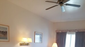 A hotel room with two beds, a ceiling fan, bedside lamps, a telephone, and a window with curtains. - Budget Host Royal Gorge Inn (Canon City)
