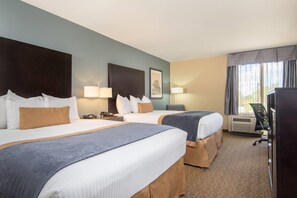 Quarto de hotel com duas camas, uma escrivaninha, uma cadeira, uma televisão e uma janela com cortinas.