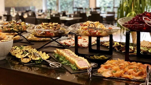 A buffet with various dishes, including salads, meats, and cheeses, arranged on a counter. - Hôtel Inn Paris CDG Airport (Roissy-en-France)