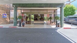 A hotel entrance with a covered walkway, glass doors, and potted plants. - Hôtel Inn Paris CDG Airport (Roissy-en-France)