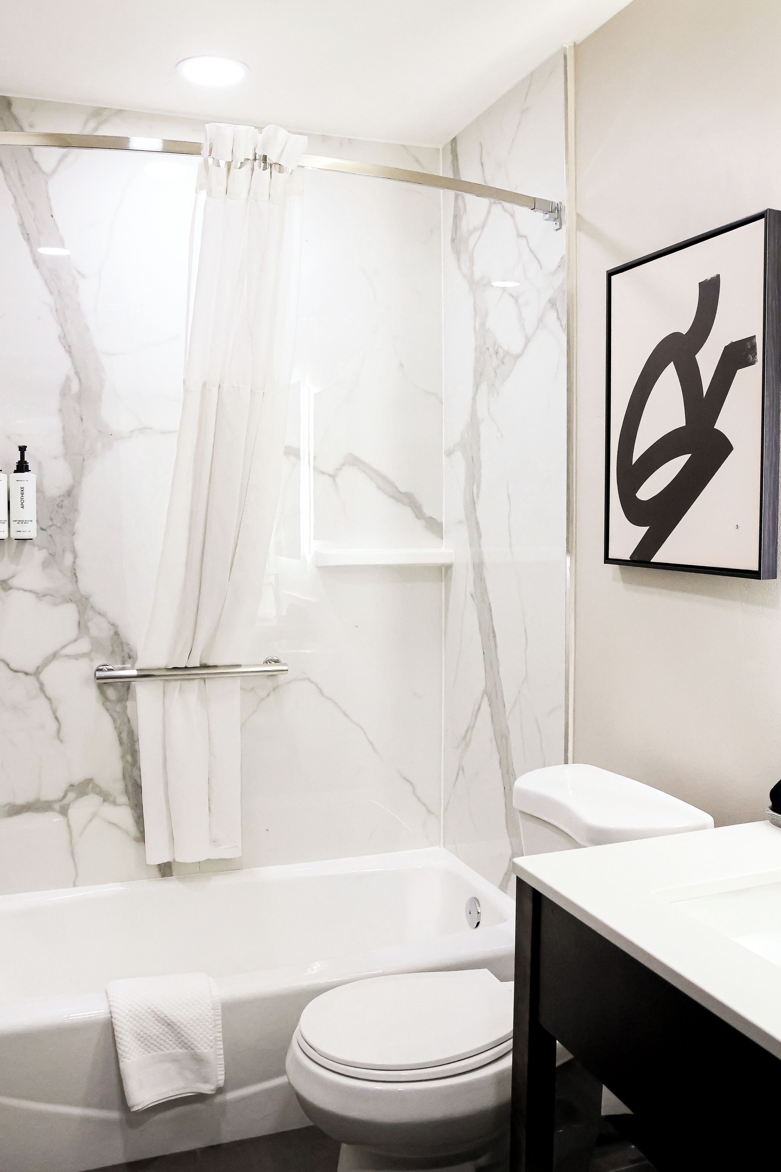 Un baño moderno con ducha de mármol, inodoro blanco y lavamanos.