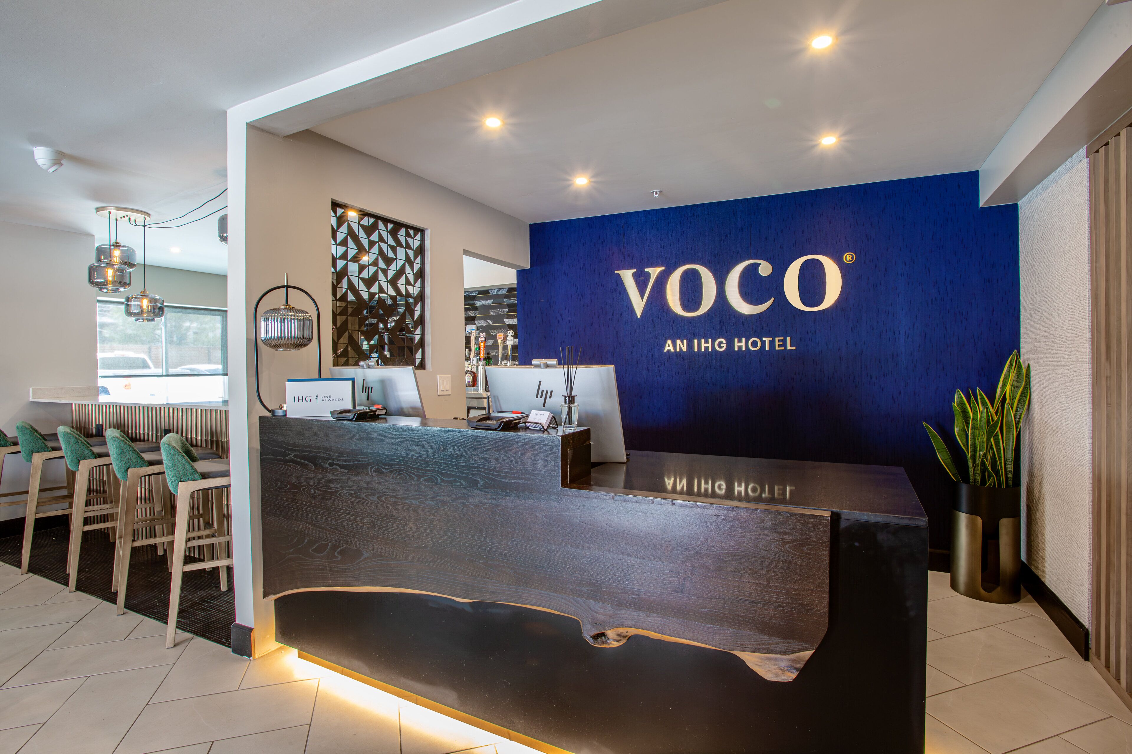 A reception desk with a blue wall behind it, a wooden reception counter, and a seating area with chairs.
