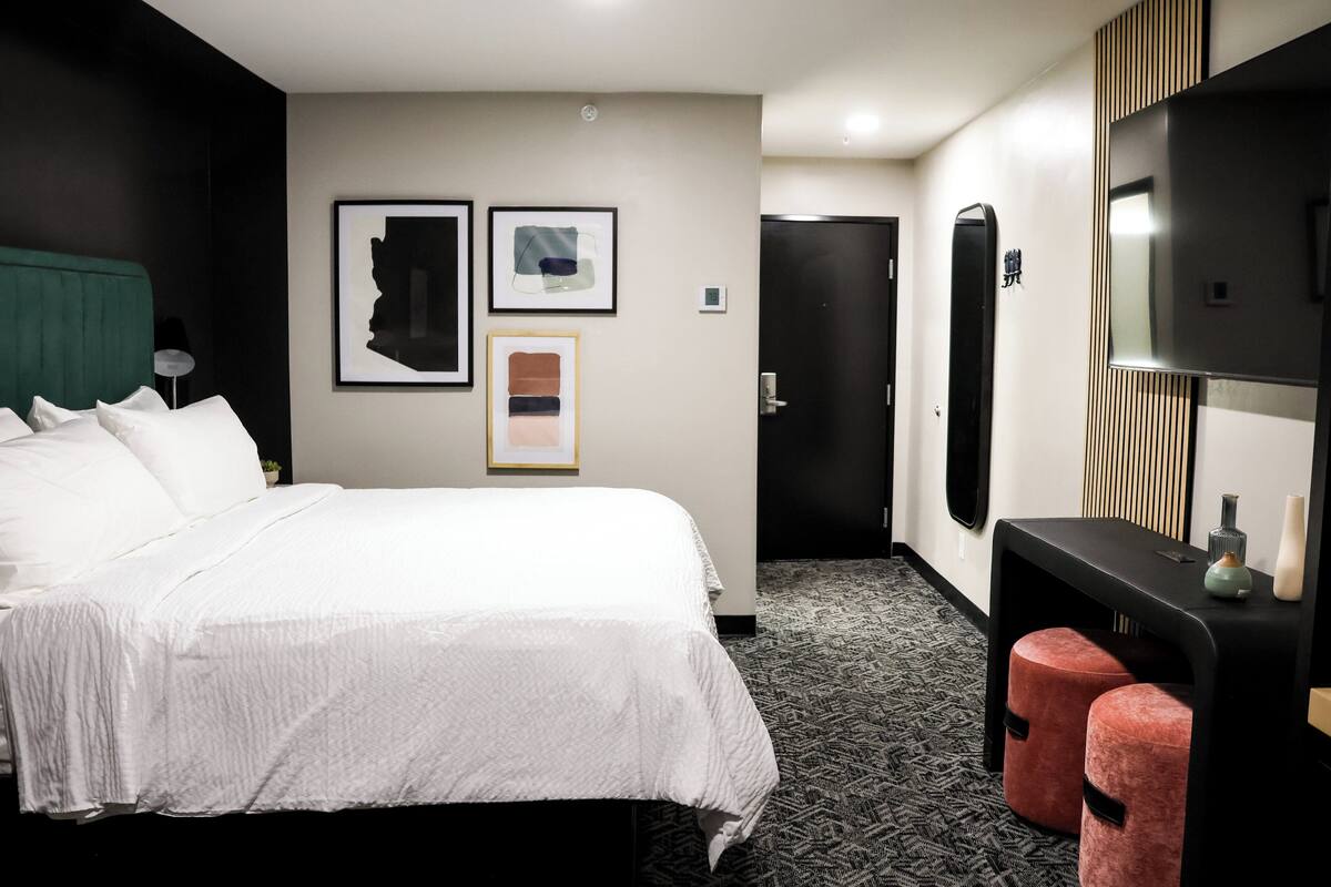 Habitación de hotel con una cama grande, un escritorio con silla, un televisor de pantalla plana y obras de arte en las paredes.