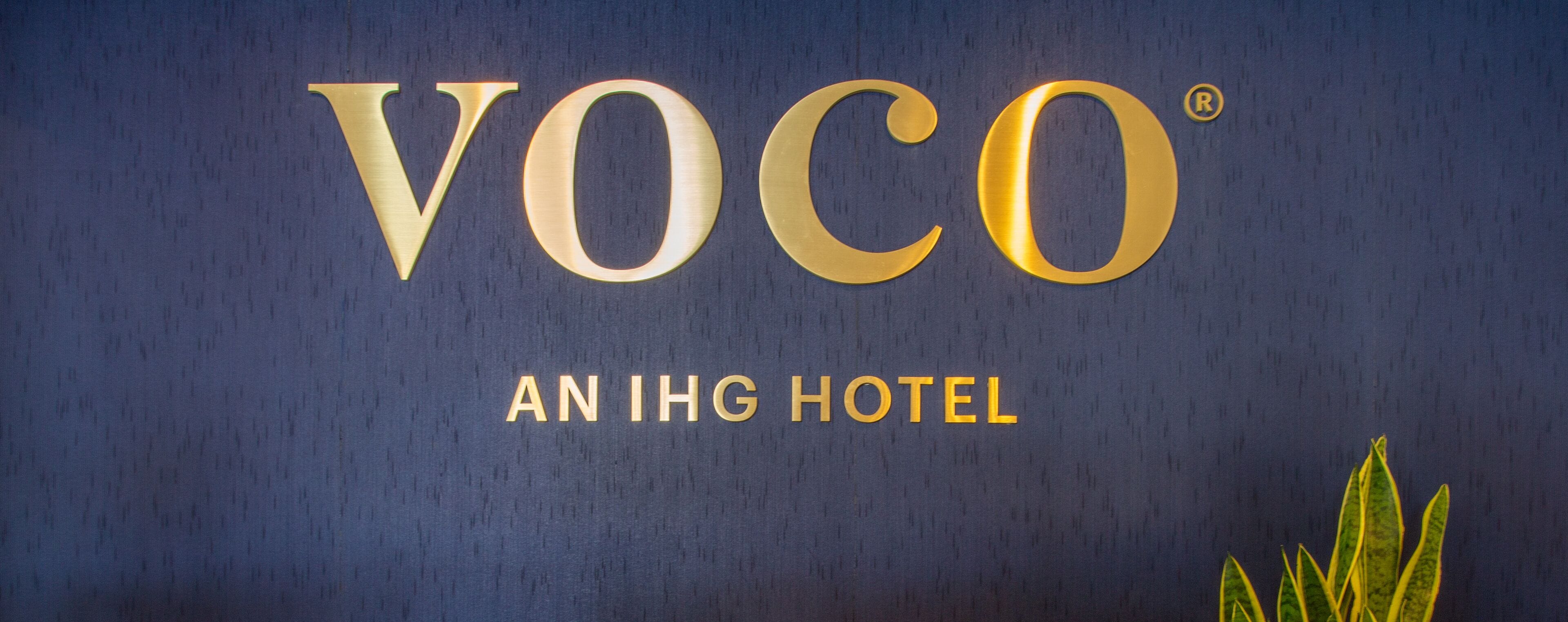 A sign with the text "VOCO" and "AN IHG HOTEL" on a dark background.
