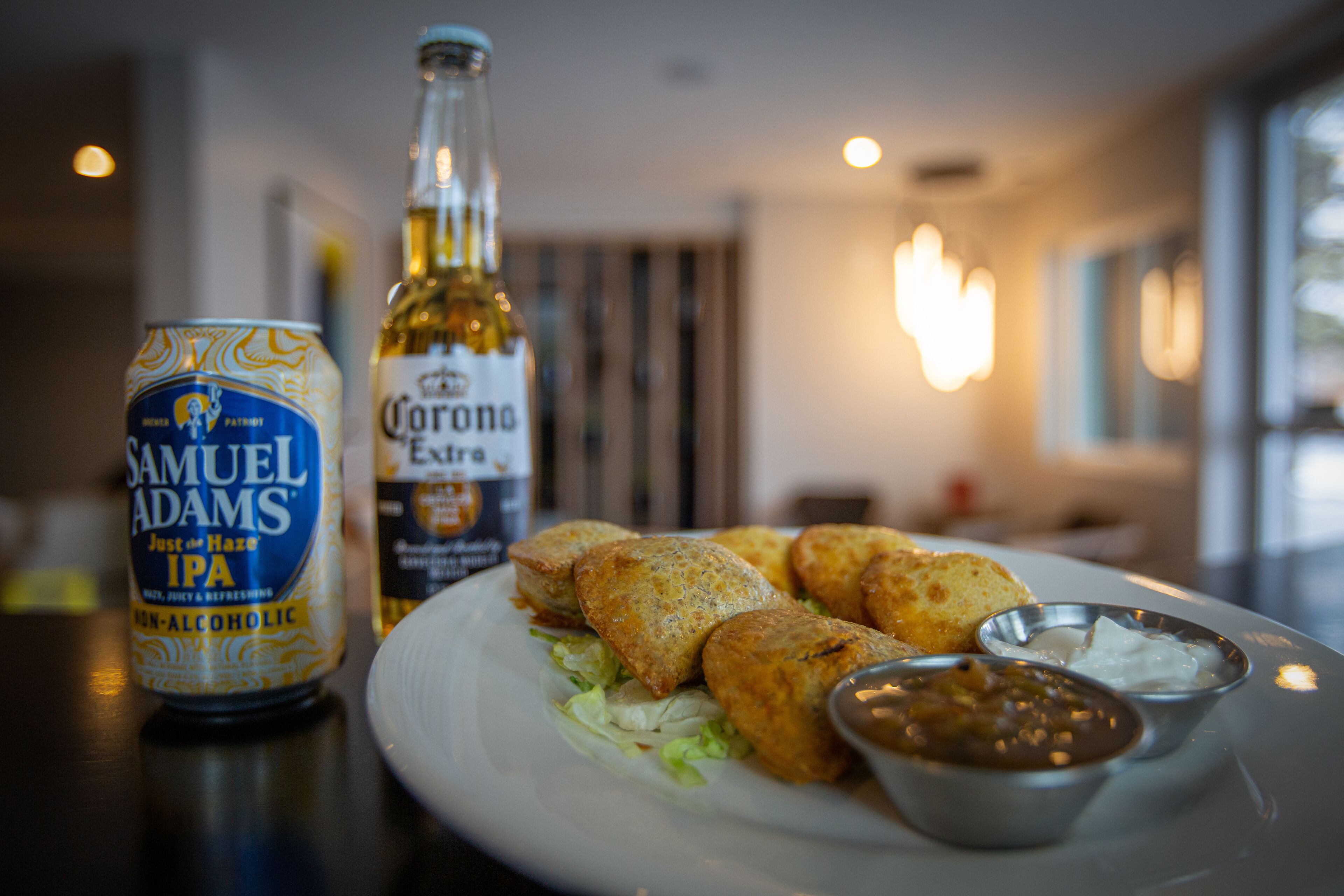 Une assiette de nourriture, une bouteille de bière et une canette de Samuel Adams IPA.