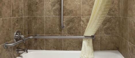 A bathroom with a bathtub, grab bar, and tiled walls.