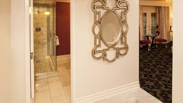 Relax in this inviting space with a glass-enclosed shower, ornate mirror, and cozy seating area.