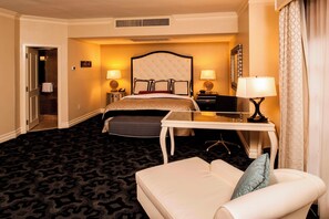 A hotel room with a large bed, a desk with a chair, a sofa, and two bedside tables with lamps. - The Siena Hotel, Autograph Collection (Chapel Hill)