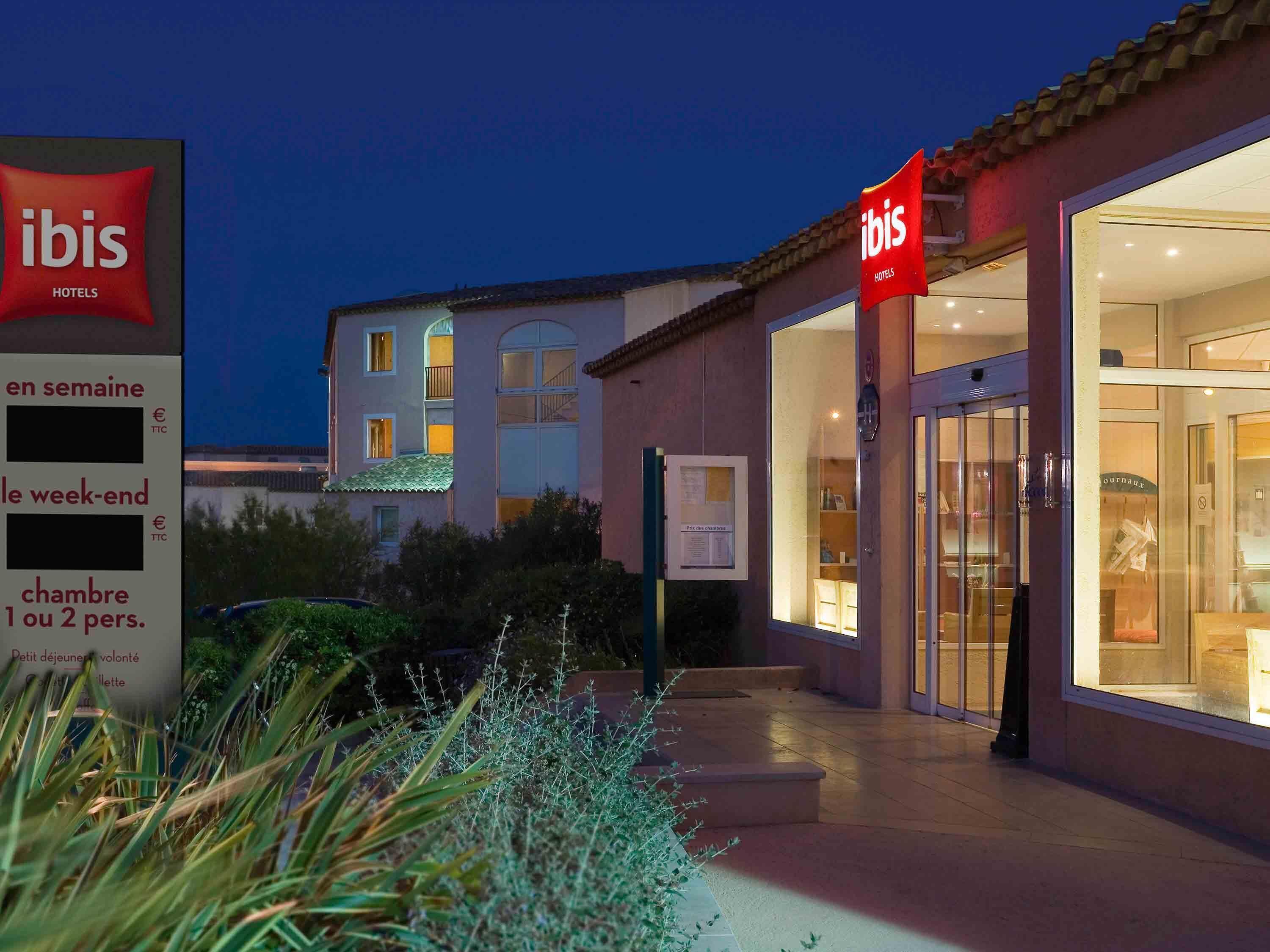 A hotel entrance with a sign indicating 'ibis HOTELS' and a glass door leading inside.