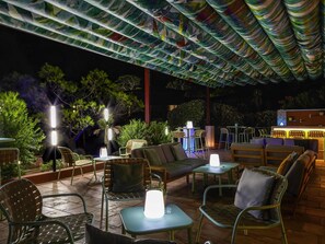 An outdoor seating area with tables and chairs, a sofa, and a bar area with stools.