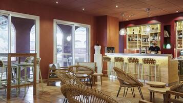 A bar area with wicker chairs, a bar counter, and shelves with bottles.