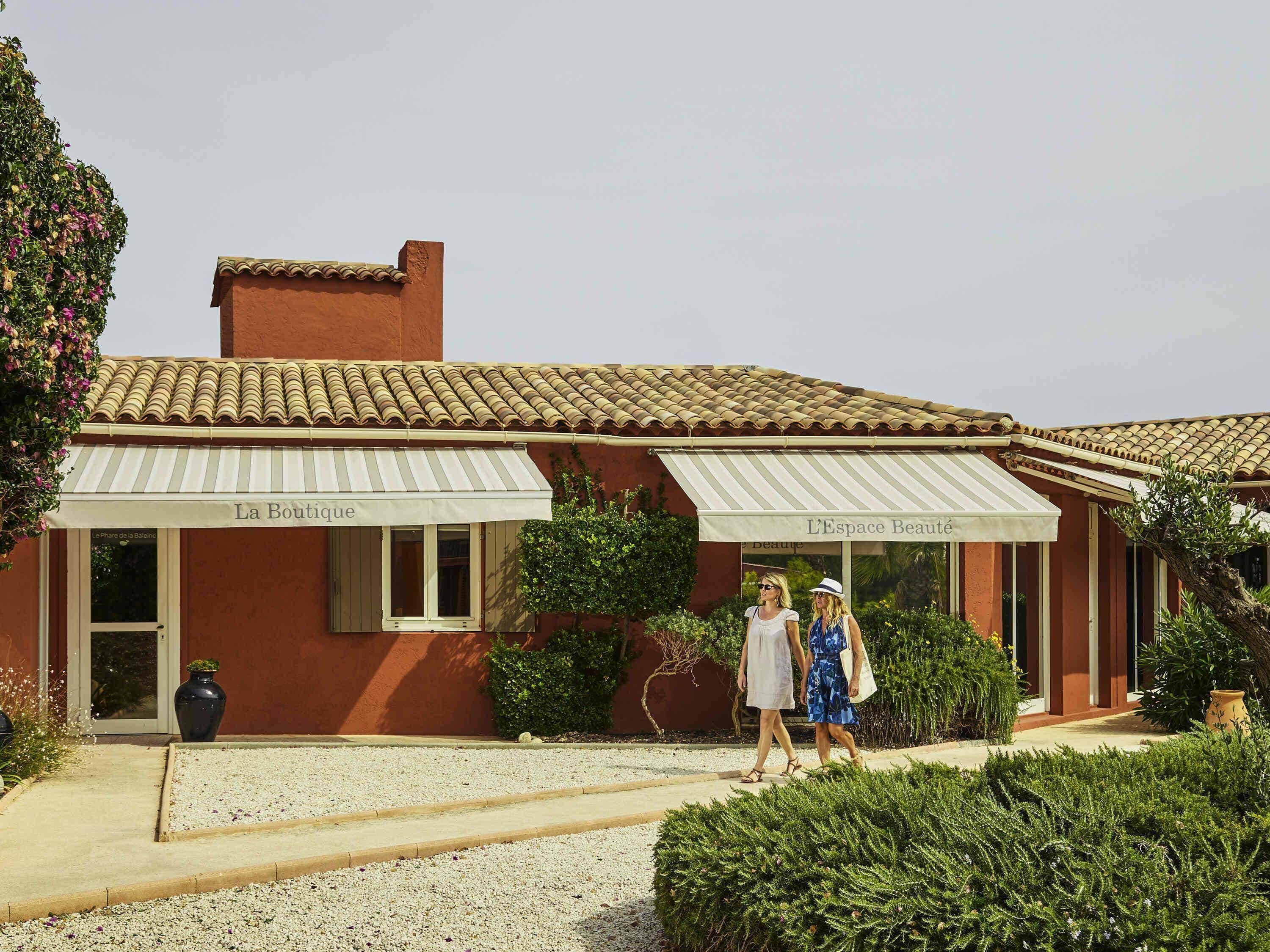 A building with a tiled roof and two awnings labeled 'La Boutique' and 'L'Espace Beauté'.