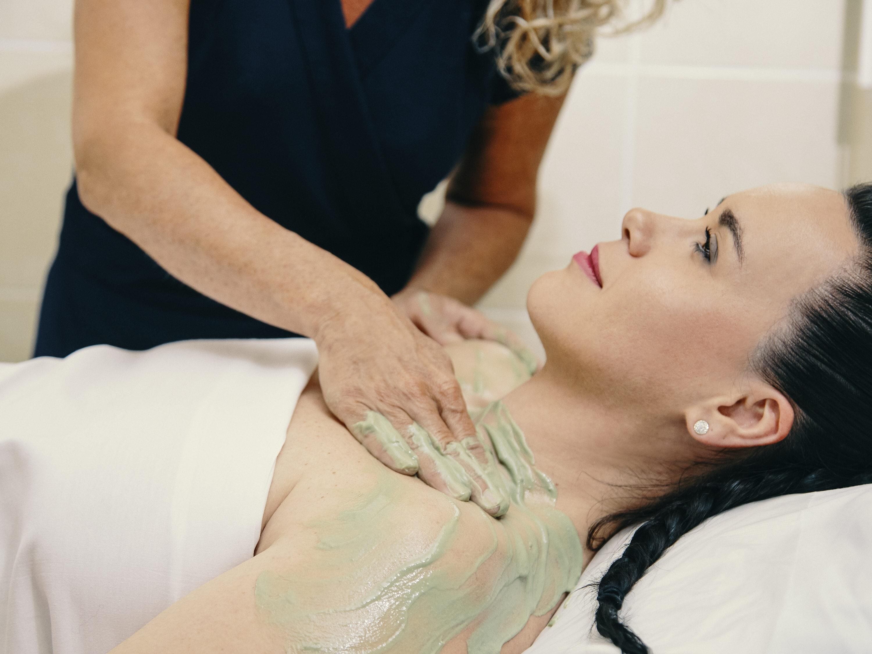 A person receiving a massage with a green substance on their back.