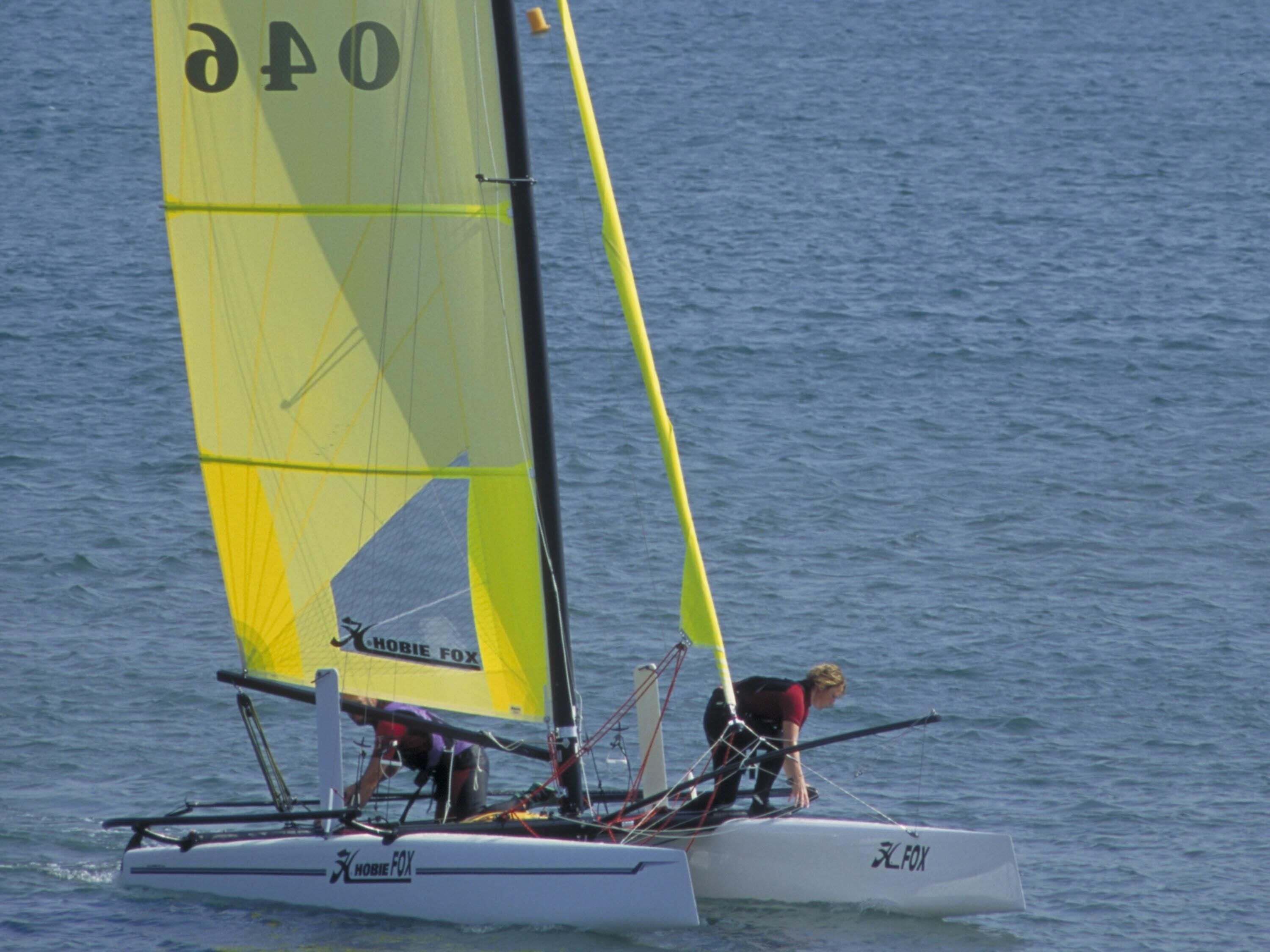 A sailboat with a yellow sail and 'FOX' branding on the hull.