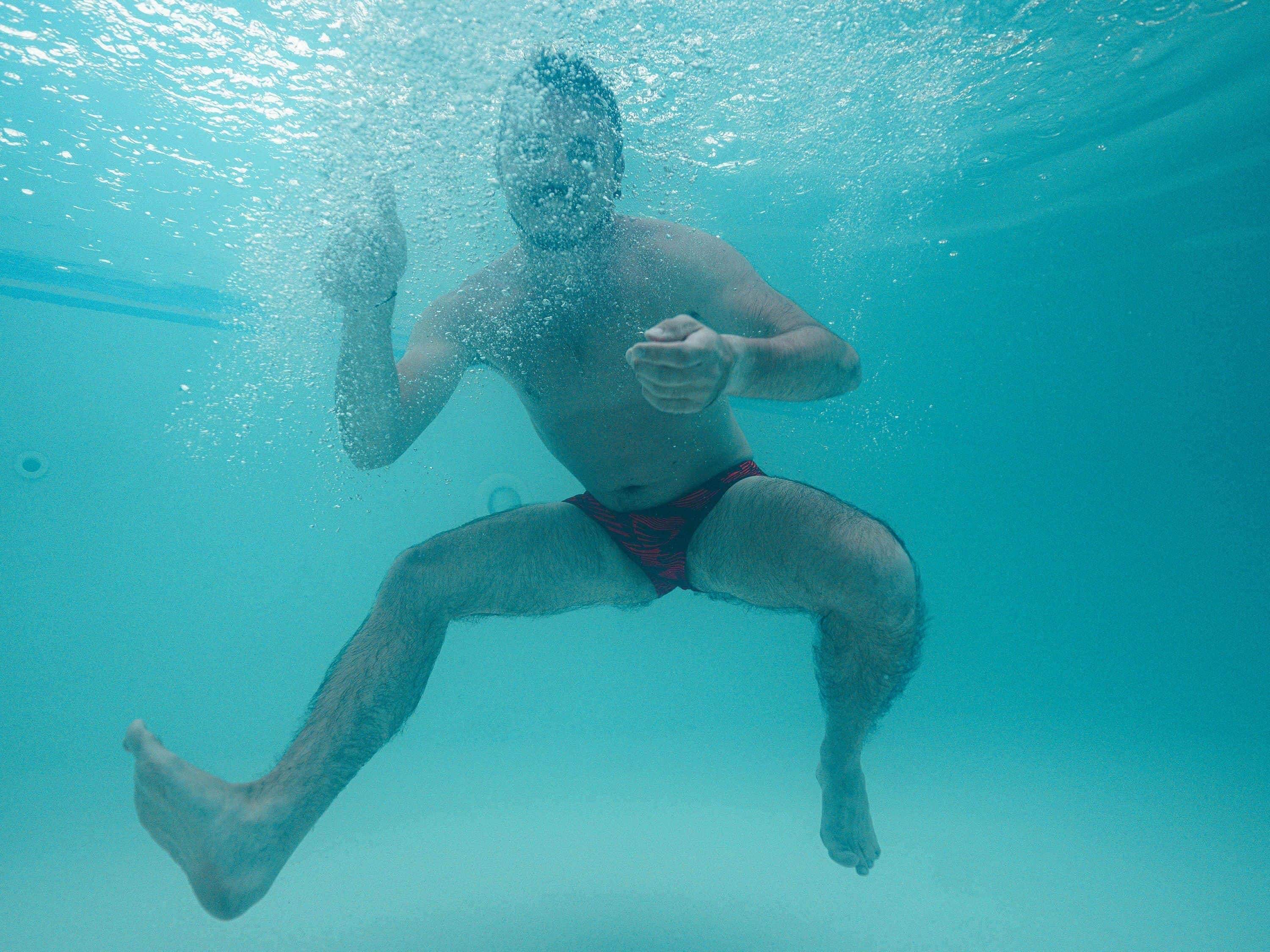 A person swimming underwater in a pool.