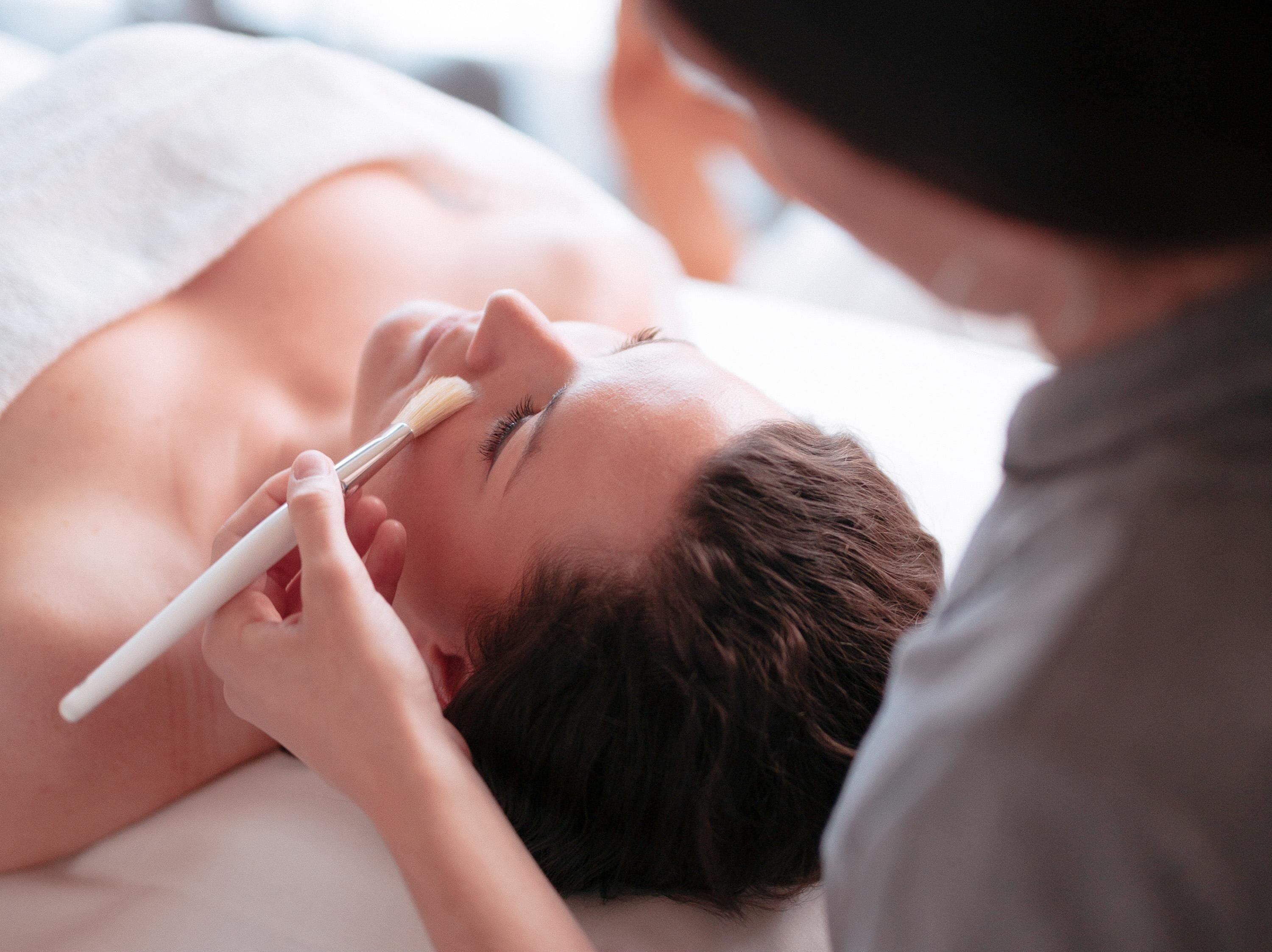 Une personne allongée qui reçoit un soin du visage.