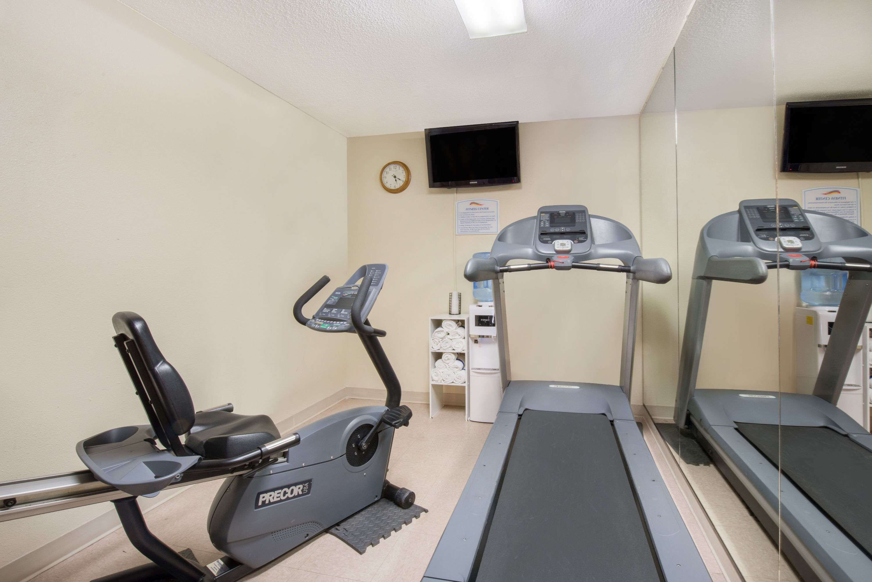 Een fitnessruimte met een loopband, een elliptische trainer en een hometrainer.