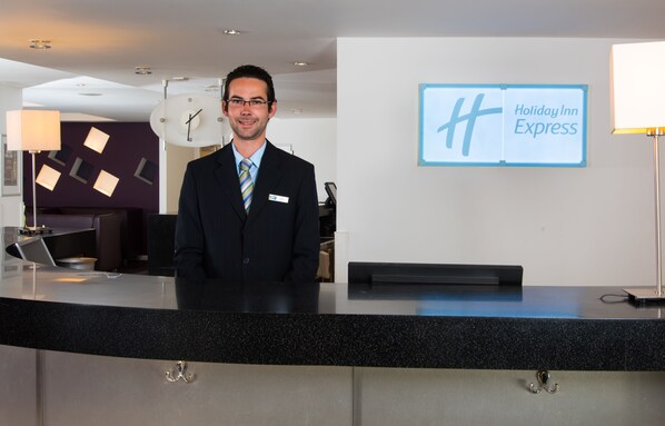 A hotel reception desk with a clock, a Holiday Inn Express sign, and a modern interior design.