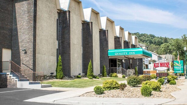 A hotel with a modern brick facade, a covered outdoor area, and a sign for 'Quality Inn' and 'Liberty St. Ale House'.